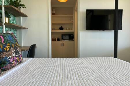 1 dormitorio con 1 cama blanca y TV en Ocean View Studio Manhattan Beach, en Manhattan Beach