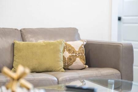 a couch with two pillows and a glass table at The Warhol - Pet-Friendly Apartment in Bentonville