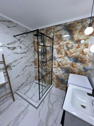 a bathroom with a sink and a marble wall at EightApartament in Bistriţa