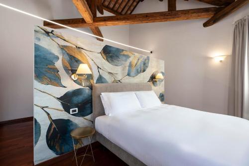 洛尼戈的住宿－Hotel Alle Acque，卧室配有一张大床,墙上挂有绘画作品