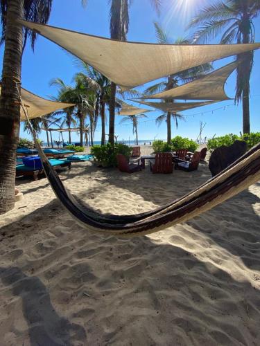 a hammock on a beach with palm trees and the ocean at Bambuddha Centro Holistico in Barra Vieja