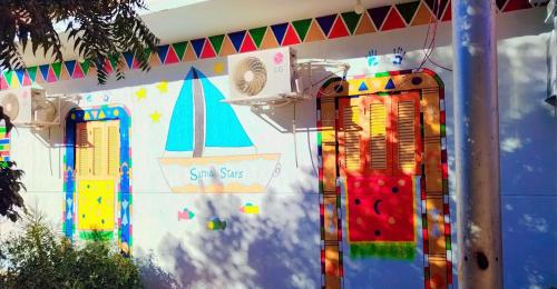 eine Wand mit einem bunten Wandbild eines Bootes und Fenstern in der Unterkunft Sama Stars Hotel in Abu Simbel