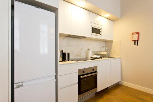 a kitchen with white cabinets and a microwave at RVA - Porto Central Flats in Porto