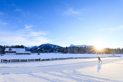 a person walking on the snow with the sun in the background at Landhaus Wieser in Ramsau am Dachstein