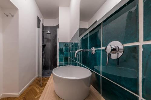 a bathroom with a tub and a green tiled wall at L'Incanto House in Salerno