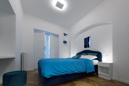 a bedroom with a blue bed and a white wall at L'Incanto House in Salerno