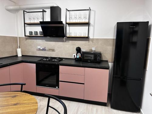 a kitchen with pink cabinets and a black refrigerator at elisio - Glide Studio in Braşov
