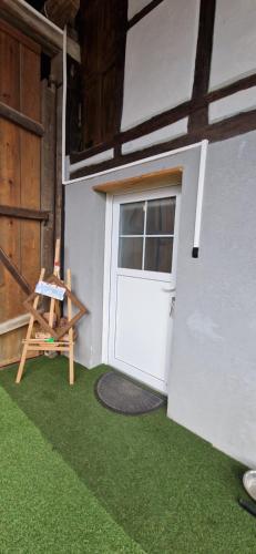 a garage with a white door and green grass at Atelier d Antoine in Saasenheim
