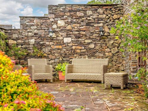 two chairs and a stone wall in a garden at 3 Bed in Buttermere 88773 in Buttermere