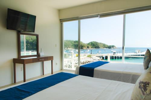 a bedroom with two beds and a view of the ocean at La Playa departamento suites in Santa Cruz Huatulco