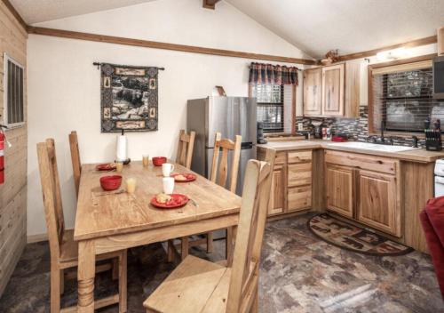 a kitchen with a wooden table and a refrigerator at Canyon Cabins in Ruidoso