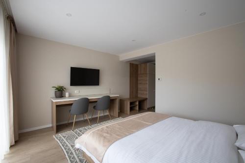 - une chambre avec un lit et un bureau avec une télévision dans l'établissement CASA ENCIAN, à Colibiţa