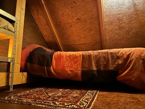 a bed in a room with a rug on the floor at Tiny house for 2 with private garden in Utrecht