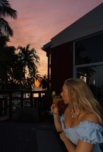 a woman sitting on a balcony drinking a glass of wine at Silver Oasis Maldives in Huraa