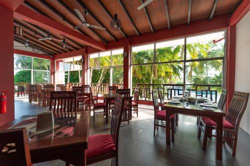 a restaurant with tables and chairs and large windows at Silver Oasis Maldives in Huraa