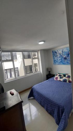 Un dormitorio con una cama azul y una ventana en APARTAMENTO CHAPINERO CENTRAL, en Bogotá
