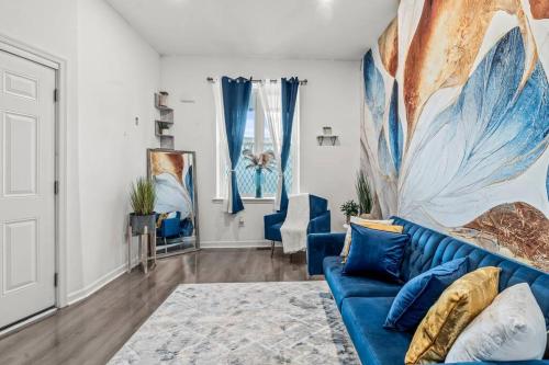 una sala de estar con un sofá azul y una pintura en The Blue Luxe Apartment West Philadelphia, 10mins Center City, Free Parking en Filadelfia