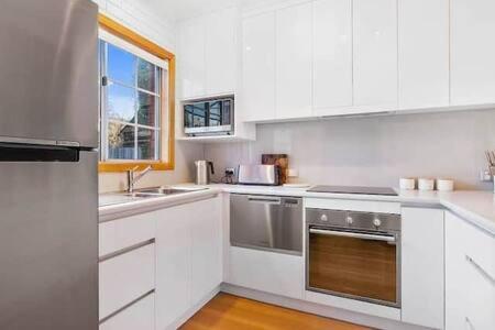 a kitchen with white cabinets and stainless steel appliances at Cosy renovated 2 bed villa in superb location in Hobart