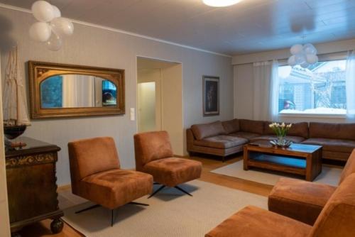 sala de estar con sofá, sillas y mesa en Villa Närhi 230 m2 upea talo rauhallisella alueella, en Seinäjoki