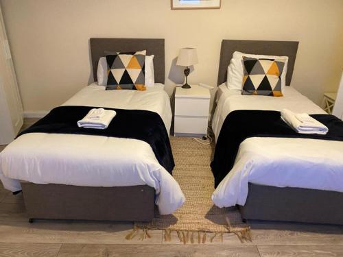 a bedroom with two beds with white and black sheets at Comfortable 2beds house 4 contractors & staycation in Leeds
