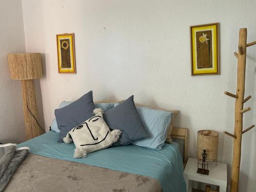 a teddy bear sitting on a bed with blue pillows at Ras el hanut appartamento a guéliz in Marrakech