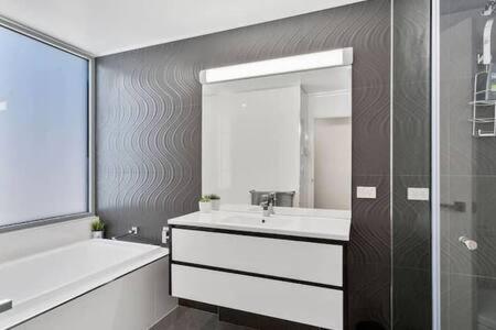 La salle de bains est pourvue d'un lavabo, d'une baignoire et d'un miroir. dans l'établissement New Architect designed Coastal retreat-water views, à Hobart