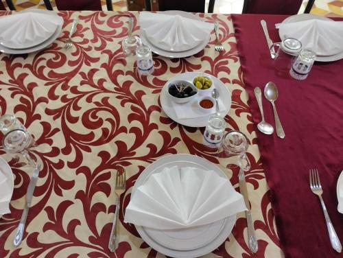 a table with white plates and silverware on a purple table cloth at El Menzeh Foundation in Rissani