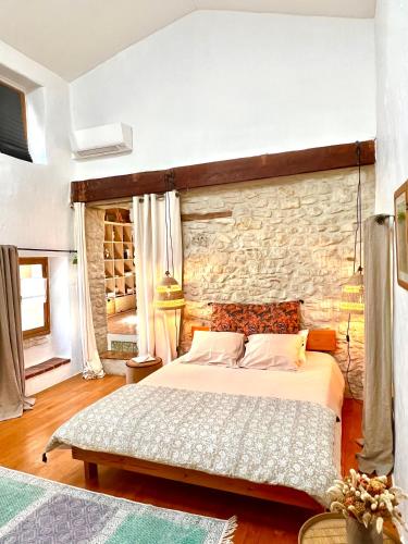 une chambre avec un lit et un mur en pierre dans l'établissement Maison typique provençale - Piscine privée - Clim, à Collorgues