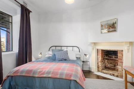 a bedroom with a bed and a fireplace at Bostane Cottage on West Hobart Hill in Hobart