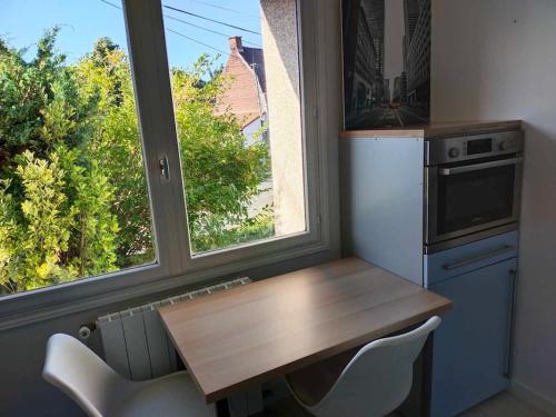 a kitchen with a table and two chairs and a window at La maison aux escargots *Jacuzzi* in Hénin-Beaumont