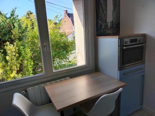 eine Küche mit einem Tisch, 2 Stühlen und einem Fenster in der Unterkunft La maison aux escargots *Jacuzzi* in Hénin-Beaumont