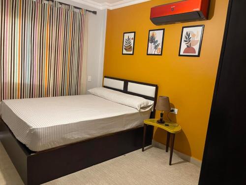 ein kleines Schlafzimmer mit einem Bett und einer gelben Wand in der Unterkunft Quiet and distinctive apartment with a wonderful v in Madinaty