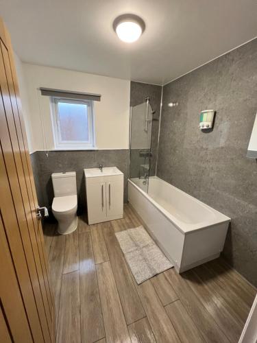 ein Badezimmer mit einer Badewanne, einem WC und einem Waschbecken in der Unterkunft Inchmurrin Townhouse, Loch Lomond in Bonhill