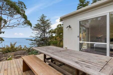 a wooden picnic table on a deck with a view of the ocean at Hidden Bay Retreat-5 Bed- 15min to Hobart in Hobart