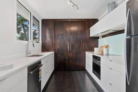 a kitchen with white counters and a wooden wall at Hidden Bay Retreat-5 Bed- 15min to Hobart in Hobart