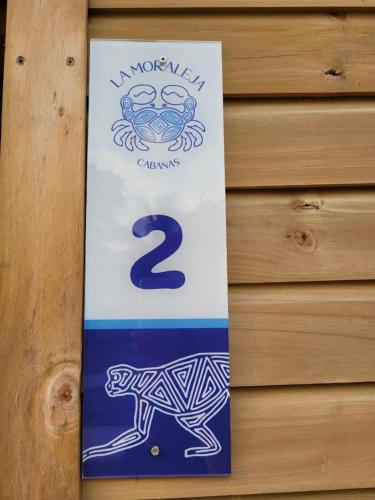 a sign on a wooden door with a dog on it at Cabañas La Moraleja Paraíso Costero in Necoclí