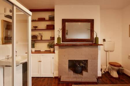 a bathroom with a fireplace with a mirror and a sink at Historic Home close to CBD 3Brm with views in Hobart