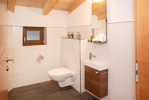 a white bathroom with a toilet and a sink at Natural Deluxe Apartments Alpbach in Alpbach