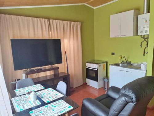 ein Wohnzimmer mit einem Flachbild-TV und einem Sofa in der Unterkunft Cabaña a pasos de la Playa in Puerto Montt