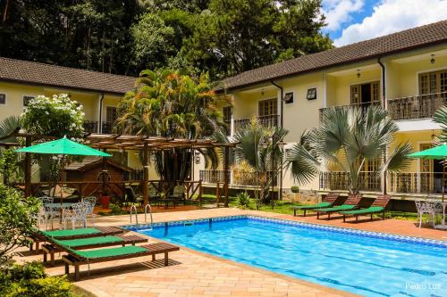 uma piscina com cadeiras e guarda-sóis ao lado de uma casa em Hotel Rio Penedo em Penedo