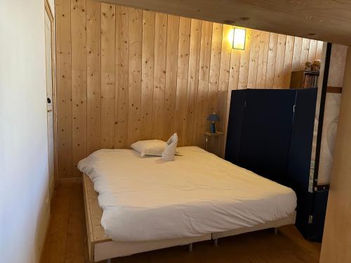 Bett in einem Zimmer mit einer Holzwand in der Unterkunft Appartement T3+Mezzanine CHARLOTTE in Courchevel
