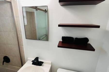 baño con espejo, aseo y lavamanos en Cozy xxl studio FREE Parking, en Miami