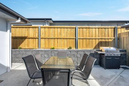 Un patio con mesa y sillas y parrilla. en New Mod Home 2 bed bath Home 12km to CBD Airport, en Rokeby