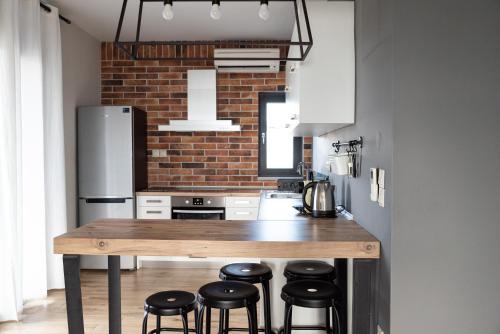 a kitchen with a wooden table and some black stools at Cos Seafront Apartments in Gerakini