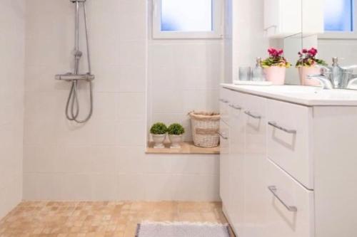 ein weißes Bad mit einer Dusche und einem Waschbecken in der Unterkunft Le temps retrouvé Maison de village de charme in Caunes-Minervois