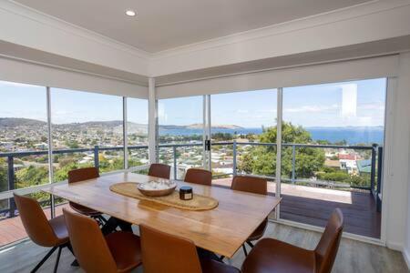 une salle à manger avec une table, des chaises et une grande fenêtre dans l'établissement River View Holiday House Sleeps 8 10min to CBD, à Hobart