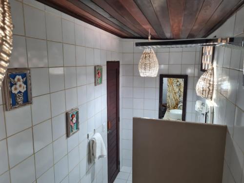 uma casa de banho com paredes em azulejos brancos e um espelho. em Porto do Sol - Chalé 25 em Pipa