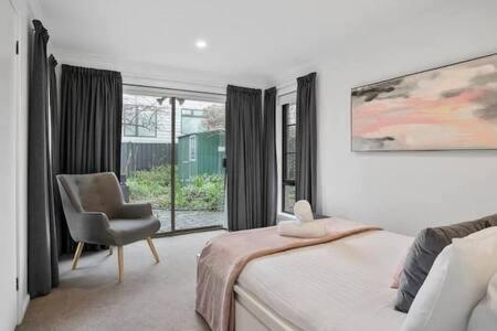 a bedroom with a bed and a chair and a window at Sandy Bay Cozy Cottage Close to CBD in Hobart