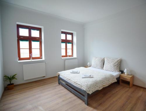 a white bedroom with a bed and two windows at Apartment U Černého Orla in Karlovy Vary