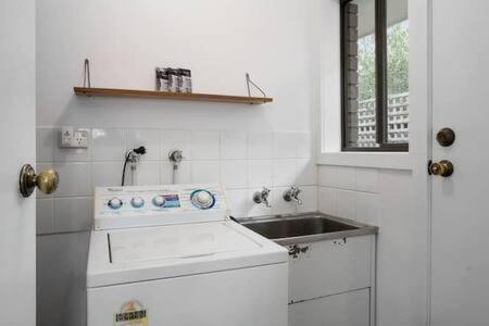 a white kitchen with a sink and a stove at Sandy Bay Cozy Cottage Close to CBD in Hobart
